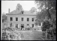 Enfants et sœurs à cornettes dans la cour d'une école de campagne.