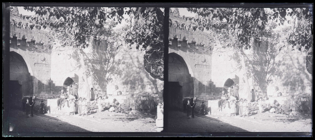Groupe de personnes à la fontaine au pied de la porte de la ville de Biredjik (Turquie).