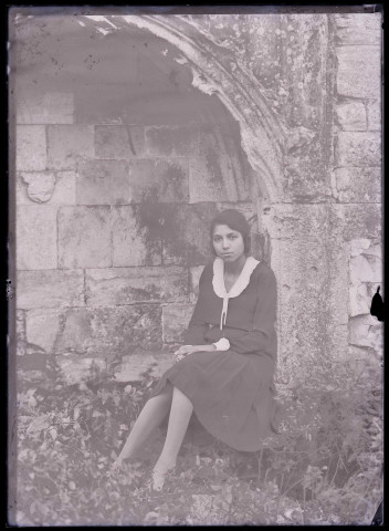 Jeune fille posant assise dans les ruines et les vestiges de l'ancienne abbaye de Saint-Pierre à Maillezais (Vendée).