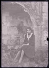 Jeune fille posant assise dans les ruines et les vestiges de l'ancienne abbaye de Saint-Pierre à Maillezais (Vendée).