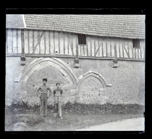 Deux ouvriers posant devant les anciennes arcatures d'un manoir normand.