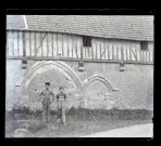Deux ouvriers posant devant les anciennes arcatures d'un manoir normand.