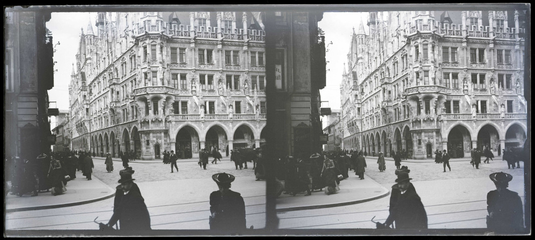 Carrefour d'une ville d'Alsace avec l'angle d'un bâtiment à passage sous arcades et statues dans la façade.