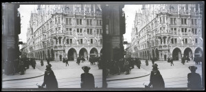 Carrefour d'une ville d'Alsace avec l'angle d'un bâtiment à passage sous arcades et statues dans la façade.