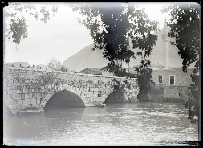 Pont en pierre traversant un fleuve et minaret.