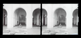 Jeune garçon assis dans la cour intérieure à arcades et fontaine d'une habitation traditionnelle algérienne.