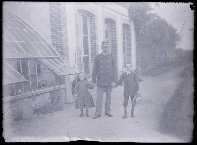 Militaire français et enfants sur un chemin devant un bâtiment.