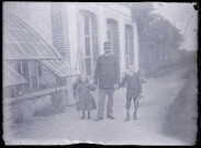 Militaire français et enfants sur un chemin devant un bâtiment.
