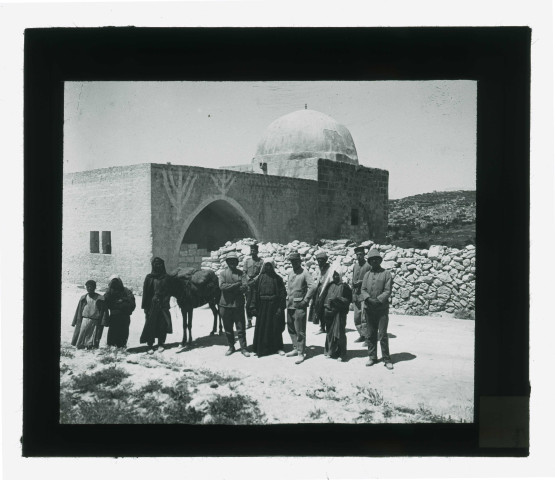 Expéditionnaires, bédouins et leur monture devant un mausolée.
