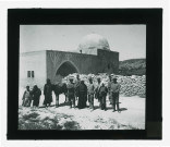 Expéditionnaires, bédouins et leur monture devant un mausolée.