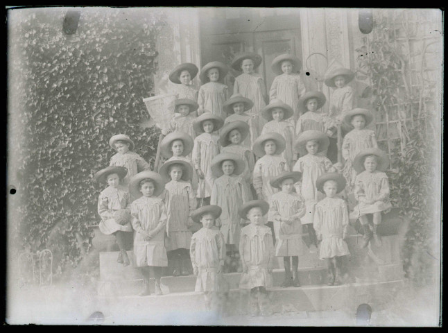 Groupe d'enfants en uniforme sur le perron d'une habitation.