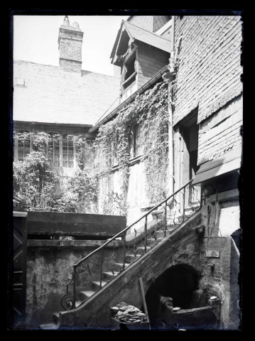 Arrière-cour avec puits et escalier de pierre d'une maison à pans de bois de Lisieux (Calvados).