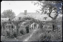 Curé dans un jardin devant une maison de la campagne normande.