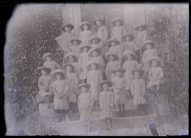 Groupe d'enfants en uniforme sur le perron d'une habitation.