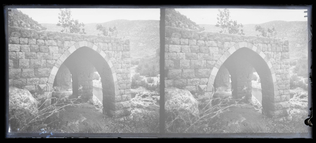 Bâtiment à arcades en pierre près d'un point d'eau.