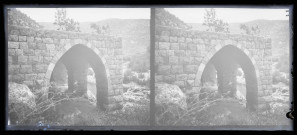 Bâtiment à arcades en pierre près d'un point d'eau.