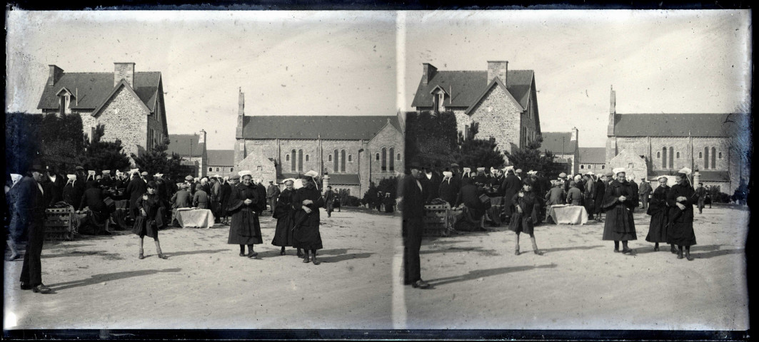 Femmes en costume traditionnel breton un jour de marché sur une place de village.