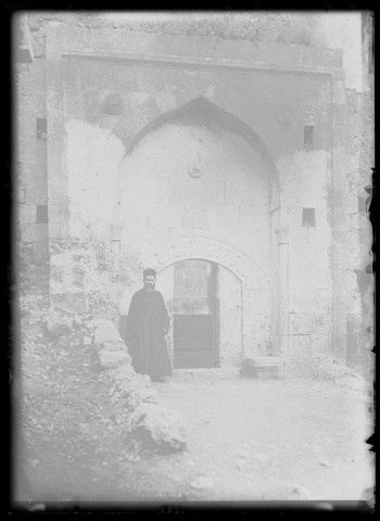 Prêtre arménien devant la porte d'un édifice en pierre à Kozan (Sis) (Turquie).