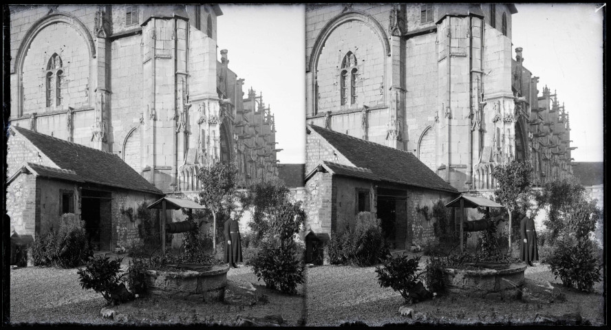 Prêtre en habit sacerdotal près d'un puits dans le jardin d'une église.