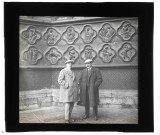 Deux hommes devant les bas-reliefs de soubassement de l'ébrasement côté gauche du portail central de la façade Ouest, dit Portail du Saint-Sauveur, de la Cathédrale d'Amiens (Somme)