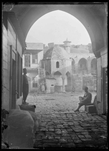 Passage donnant sur une ruelle avec à l'arrière-plan un minaret et la citadelle d'Alep (Syrie).