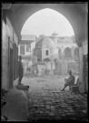 Passage donnant sur une ruelle avec à l'arrière-plan un minaret et la citadelle d'Alep (Syrie).