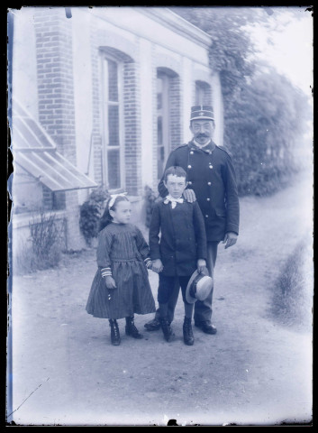 Militaire français et enfants sur un chemin devant un bâtiment.