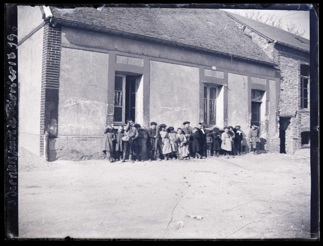 Groupe d'enfants devant le mur d'une habitation lors des trois derniers jours de février 1899.