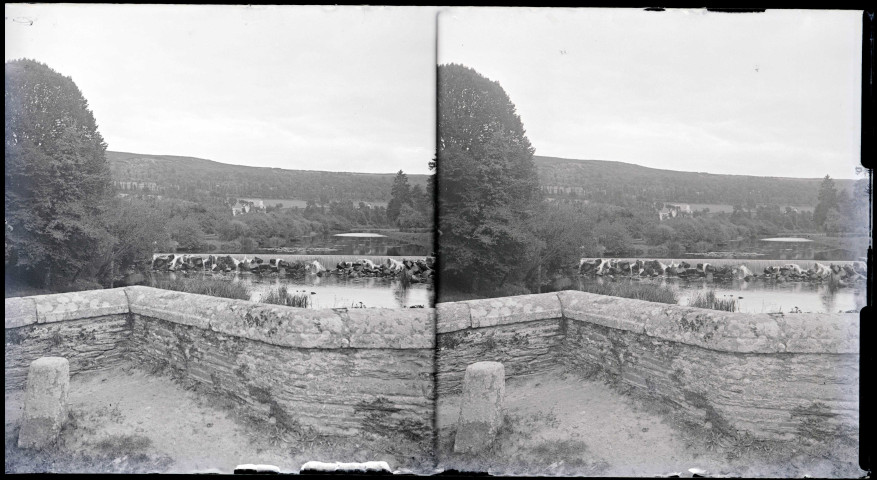 Vue sur la chaussée d'une rivière depuis un pont en pierre.